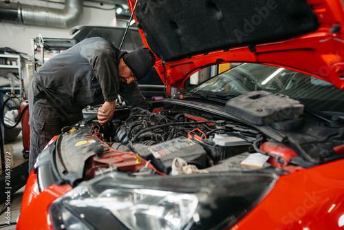 Auto mechanic checking engine in garage repair service