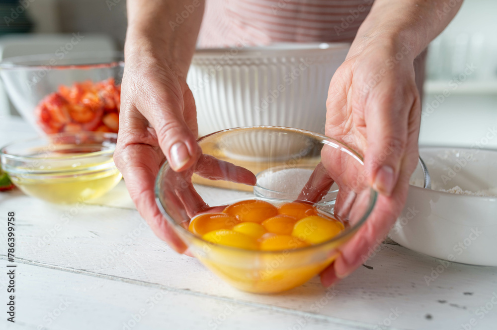 Bowl with raw egg yolks for making a cake holding by woman´s hands in the kitchen. Bowl with raw egg yolks for making a cake holding by woman´s hands in the kitchen.