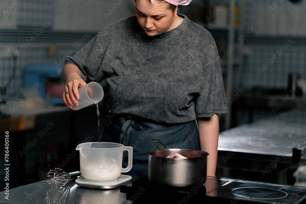 in professional kitchen pours water into a measuring container for dough