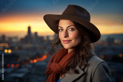 Portrait of a glad woman in her 40s donning a classic fedora in front of vibrant city skyline