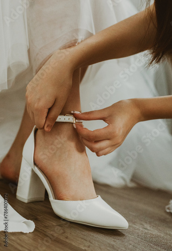 The bridesmaid helps the bride put on her shoes. © Nataliya