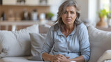 Menopause. Woman suffering from abdominal pain on sofa