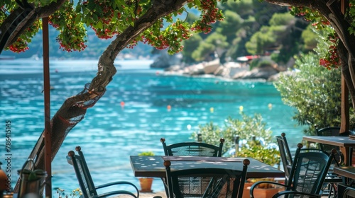 Authentic atmospheric cafe on the shore of the French Riviera under green trees overlooking clear blue water, colorful flowers in the background photo