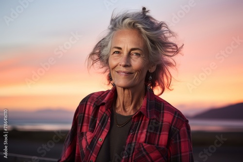 Portrait of a happy woman in her 70s wearing a comfy flannel shirt on vibrant sunset horizon