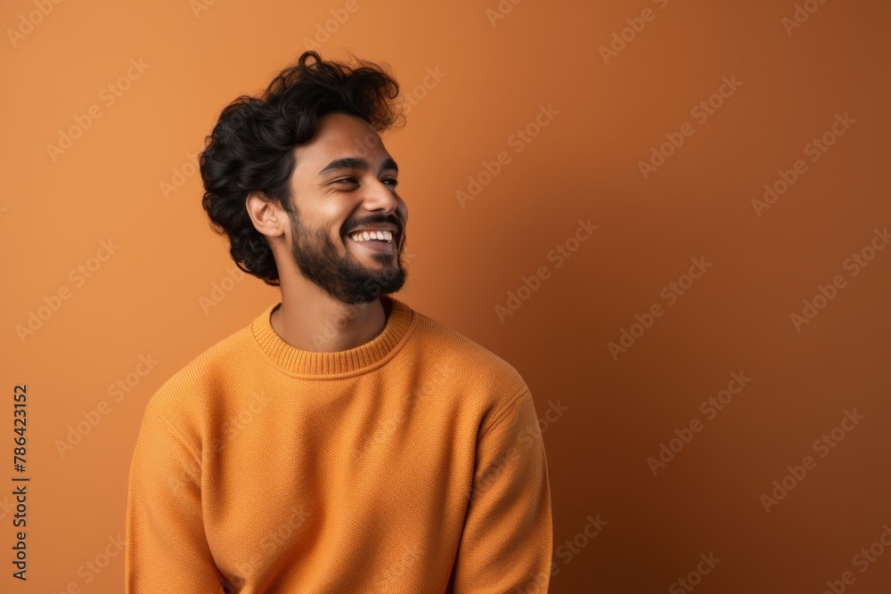 Portrait of a grinning indian man in his 20s wearing a cozy sweater in modern minimalist interior Portrait of a grinning indian man in his 20s wearing a cozy sweater in modern minimalist interior