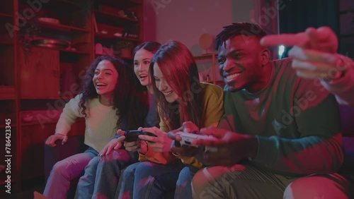Cheerful company of friends playing video games in room