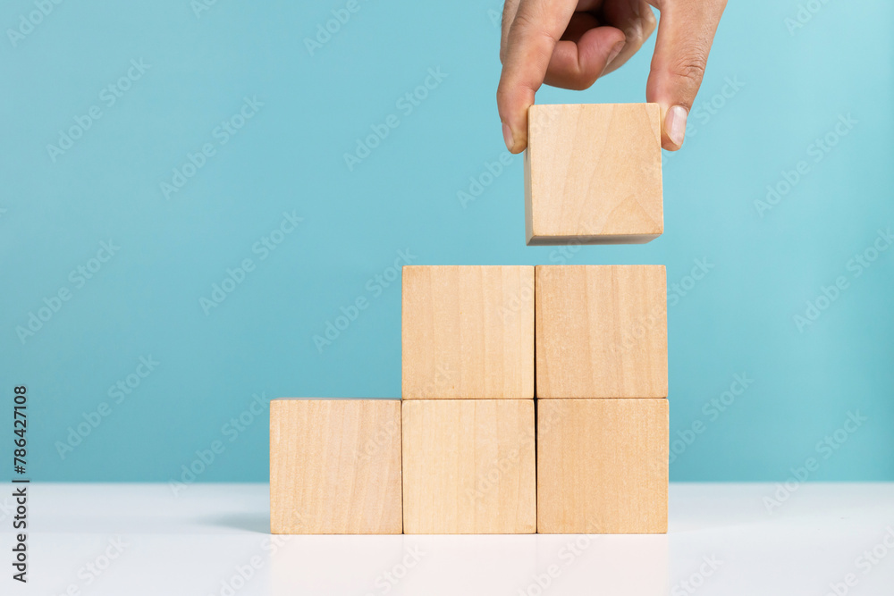 Concept for business growth or success process. Hand put last piece of wooden cube stacking as step stair Concept for business growth or success process. Hand put last piece of wooden cube stacking as step stair