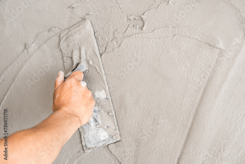 Hand plasterer plastering trowel wet cement house wall background  