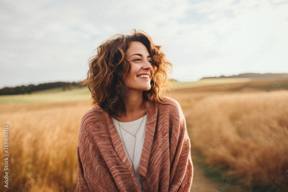 Portrait of a happy woman in her 30s wearing a cozy sweater isolated in quiet countryside landscape Portrait of a happy woman in her 30s wearing a cozy sweater isolated in quiet countryside landscape