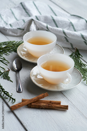 Two white ceramic cups with black tea and cinnamon sticks