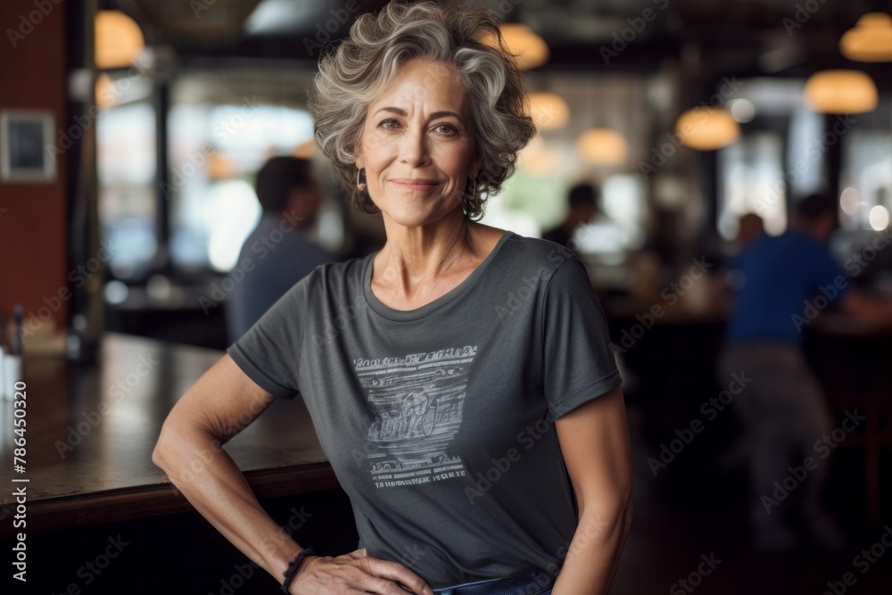 Portrait of a blissful woman in her 60s dressed in a casual t-shirt while standing against bustling city cafe Portrait of a blissful woman in her 60s dressed in a casual t-shirt while standing against bustling city cafe