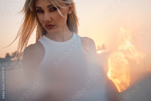 A contemplative woman is framed by a strong sun flare, creating a dramatic and moody portrait with an artistic edge