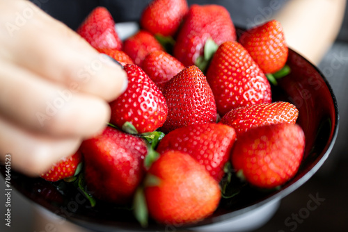 Obraz na płótnie Juicy, sweet, ripe, fresh strawberries in a plate. A handful of strawberries in a saucer. The girl takes a strawberry with her hand. w salonie