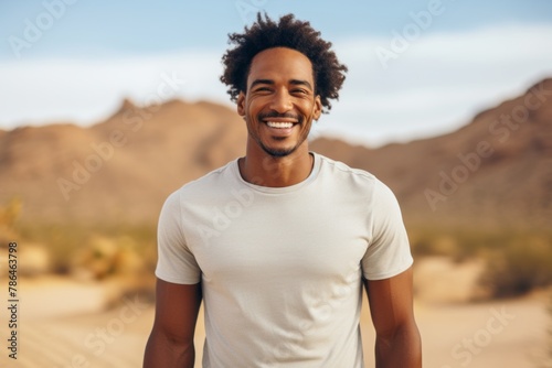 Portrait of a joyful afro-american man in his 30s dressed in a casual t-shirt isolated in backdrop of desert dunes