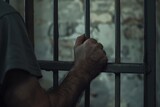 Close-up of the hands and wrists in prison, holding onto the bars with their hands, crime and punishment, violation of the law and consequences, a prisoner in prison