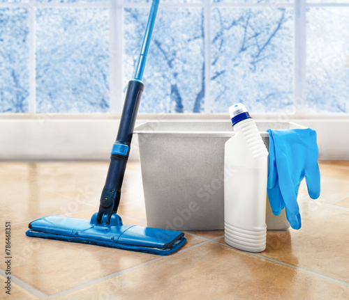 Blue Mop , bucket , spray bottle and gloves are on the tiled floor at room