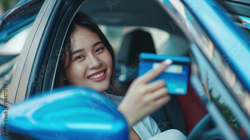 Happy beautiful Asian woman sitting inside new car blue and showing credit card pay for oil, pay a tire, maintenance on the garage. copy space for tex. photo
