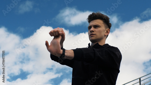 A young man stretches his wrists. Preparation for running. Exercise. Healthy Lifestyle