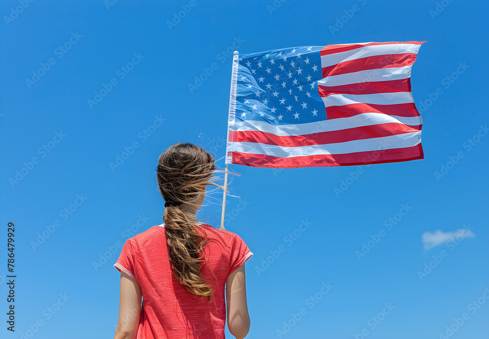 Naklejka premium Woman holding the national flag of the USA against the blue sky, representing the 4th of July, USA Independence Day.