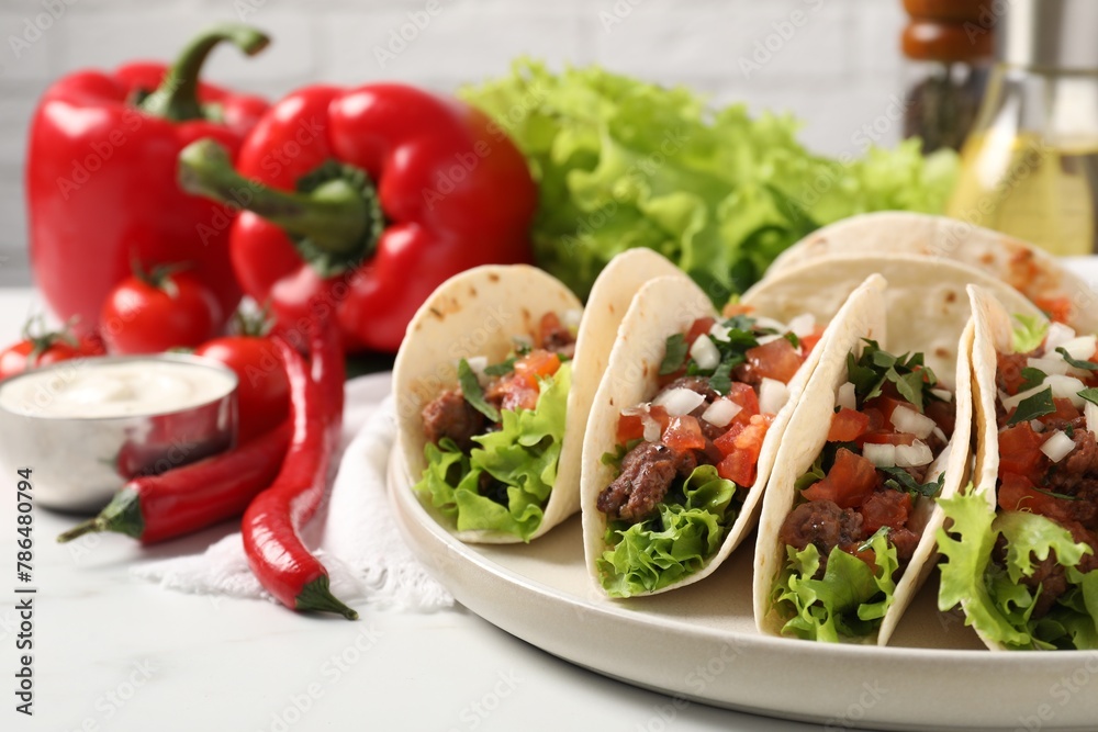 Delicious tacos with meat and vegetables on white table, closeup Delicious tacos with meat and vegetables on white table, closeup
