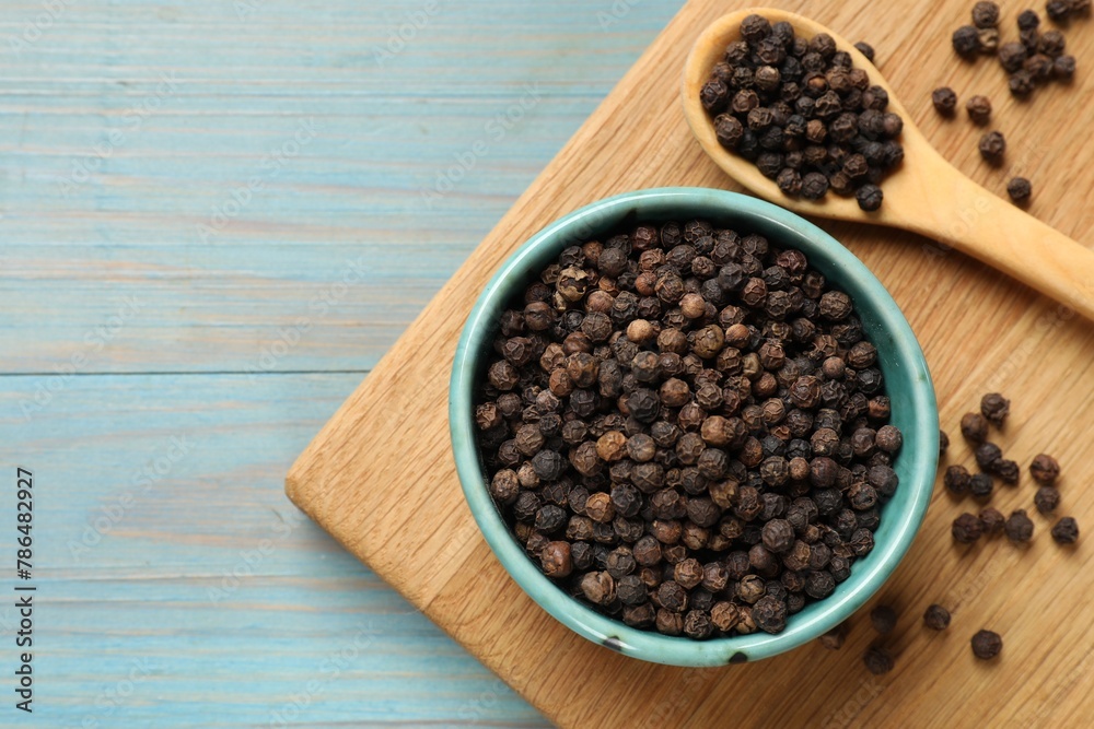 Aromatic spice. Black pepper in bowl on light blue wooden table, top view. Space for text Aromatic spice. Black pepper in bowl on light blue wooden table, top view. Space for text