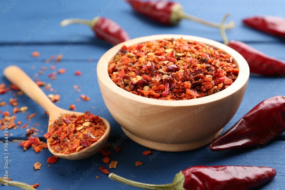 Chili pepper flakes and pods on blue wooden table, closeup Chili pepper flakes and pods on blue wooden table, closeup