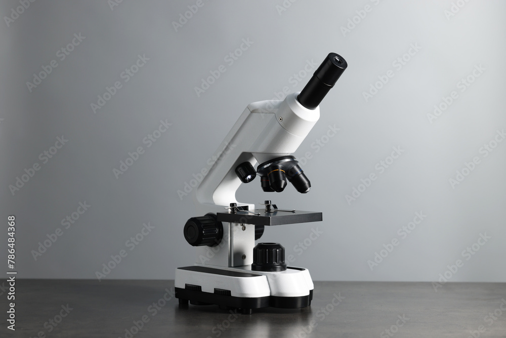 Modern medical microscope on grey table against light background Modern medical microscope on grey table against light background