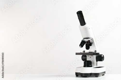 Modern microscope on white table, space for text