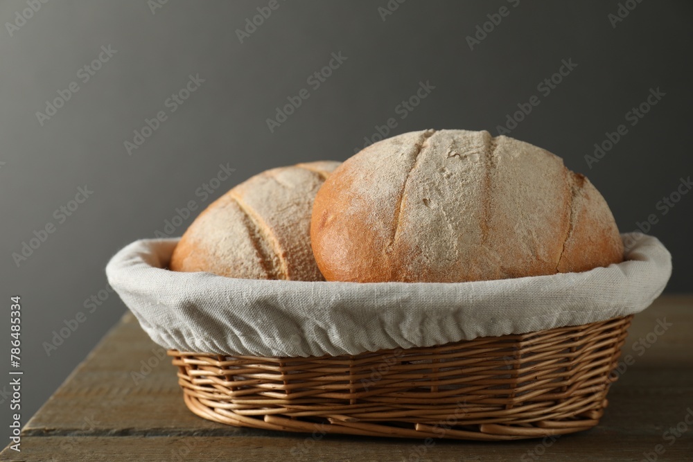 Wicker basket with fresh bread on wooden table Wicker basket with fresh bread on wooden table