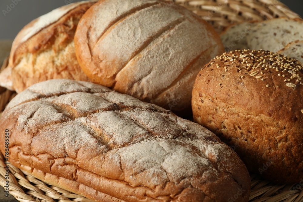 Basket with different types of fresh bread on table, closeup