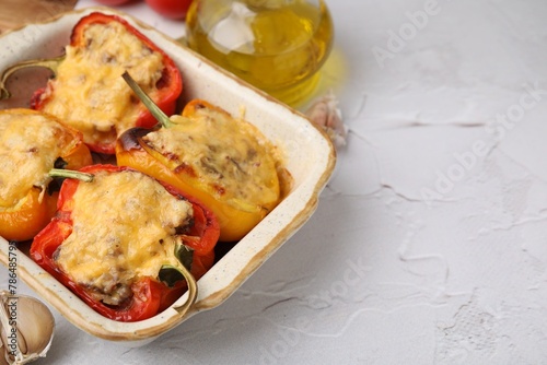 Delicious stuffed peppers in baking dish on white textured table, space for text