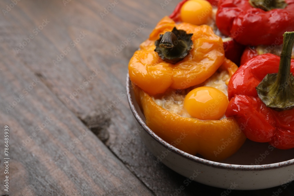 Delicious stuffed bell peppers with fried eggs on wooden table, closeup. Space for text