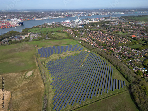 Large solar farm on the agricultural field near Marchwood village, UK. High altitude aerial view towards Southampton Docks and Marchwood Power station.