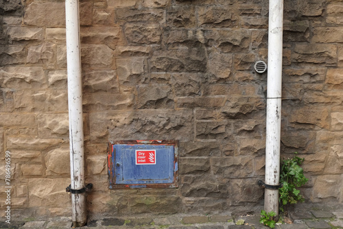 Fotografía Stone wall with two drainpipes and dry riser inlet sign, Edinburgh, Scotland