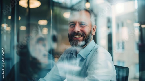 A joyful manager addressing his team in a conference room, captured through the glass window.