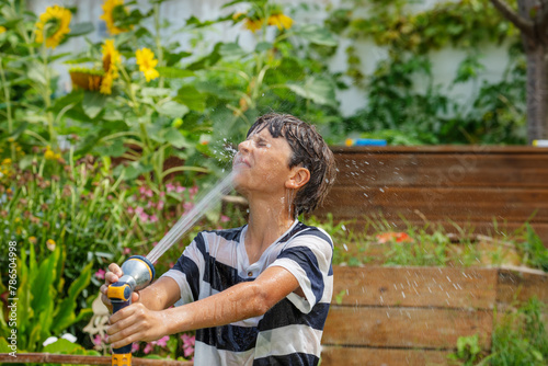 Teen cools off by playfully douse with stream of water from hose