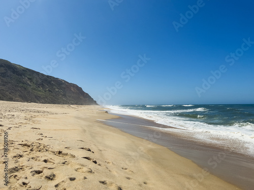 Steps on sand with cliffs and ocean waves nearby in sunny day