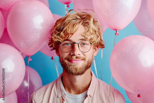 Happy blonde man with pink balloons isolated on an blue background with copy space for text, Happy birthday concept © Jane_S
