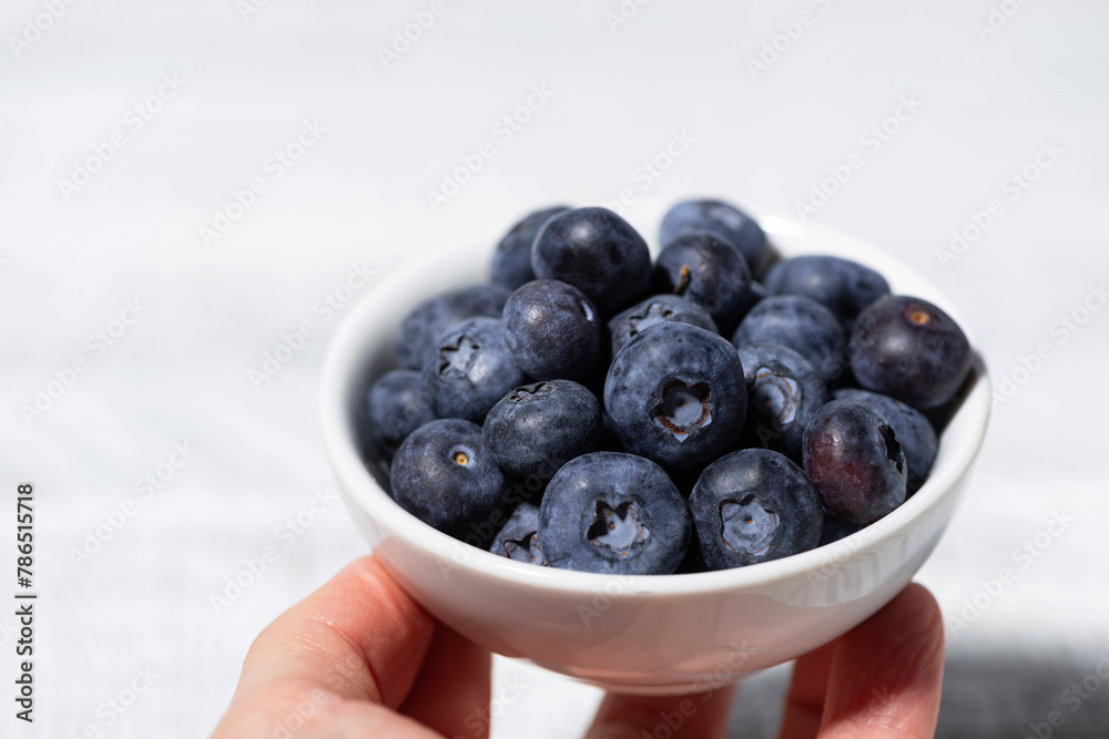 fresh blueberries in a white bowl in hand fresh blueberries in a white bowl in hand