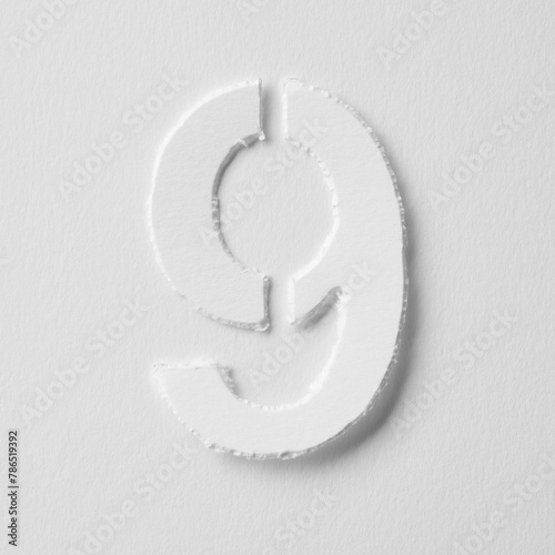 The number nine is made of white paper on a white background.