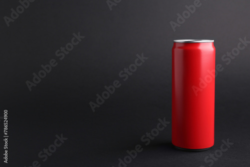 Energy drink in red can on black background, space for text