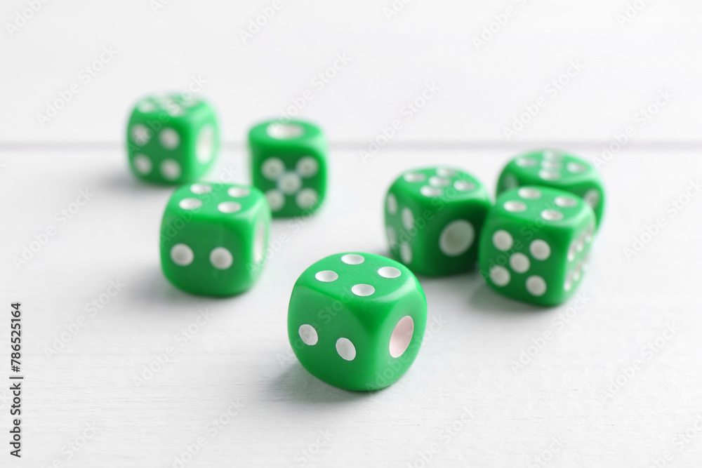 Many green game dices on white wooden table, closeup Many green game dices on white wooden table, closeup
