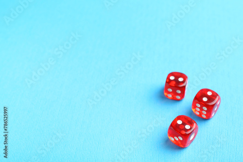 Three red game dices on light blue background. Space for text