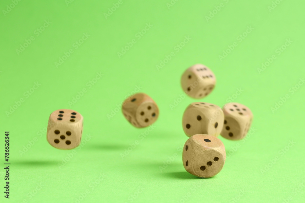 Many wooden game dices falling on green background Many wooden game dices falling on green background