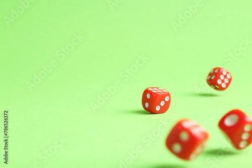 Many red game dices falling on green background. Space for text