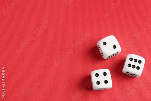 Three white game dices on red background  flat lay. Space for text
