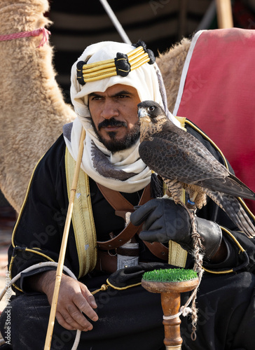 Saudi man in traditional clothing with his camel in a desert