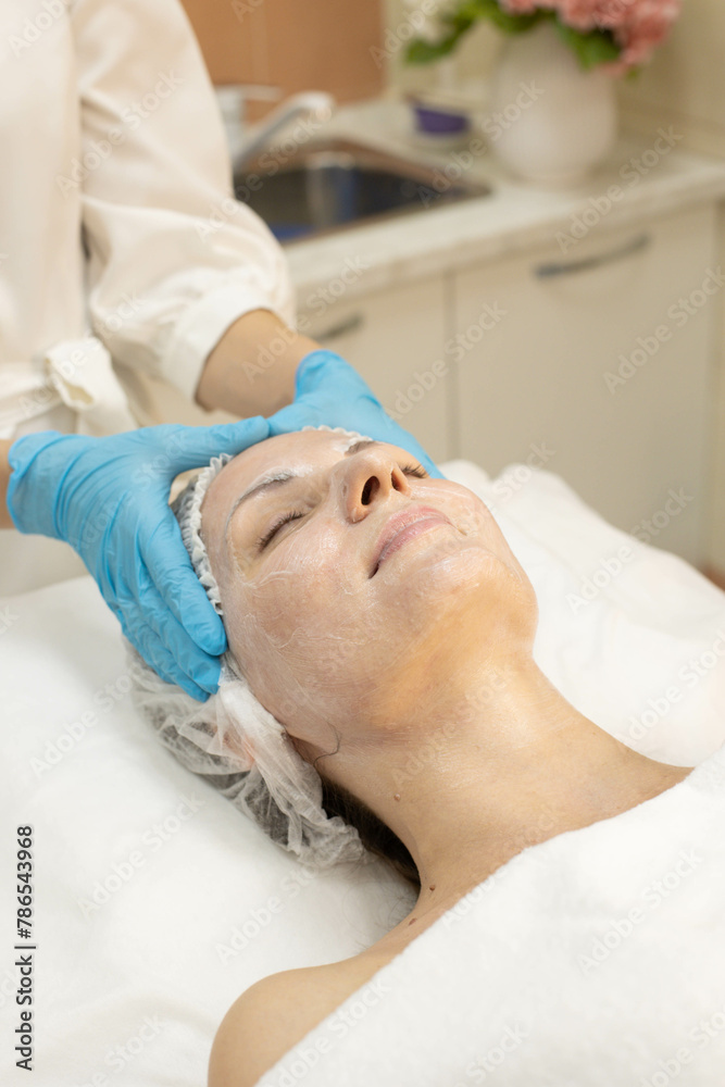 Doctor hands in gloves close-up, facial massage with cream mask, beauty clinic.