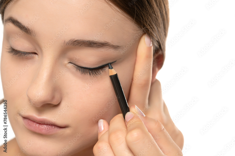 woman applying eyeliner on eyelid with pencil on a white background woman applying eyeliner on eyelid with pencil on a white background