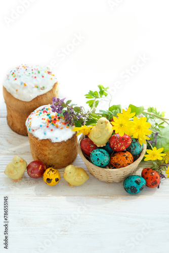 Easter cakes (Paska, Kulich), chickens toys and colorful eggs with flowers on white wooden table. Easter holiday background. Festive composition for spring season.